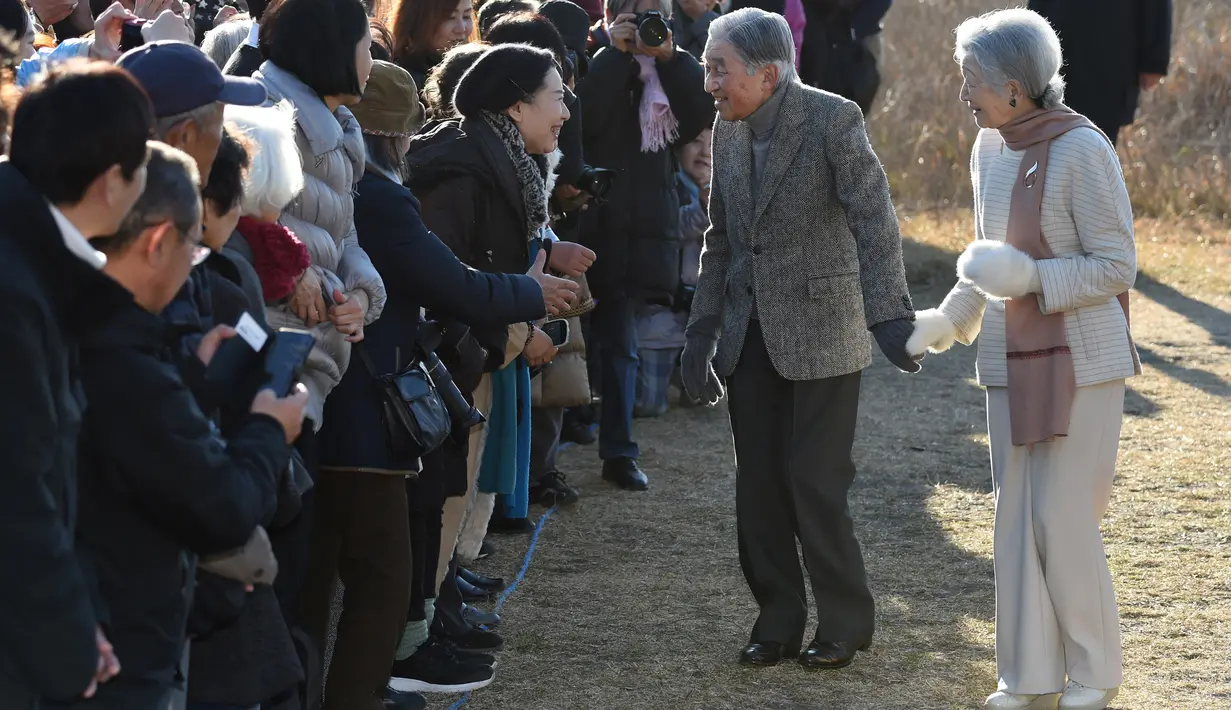 Kaisar Jepang Akihito dan Permaisuri Michiko menyapa warga saat berjalan-jalan di pantai dekat villa miliknya, Prefektur Kanagawa, Senin (21/1). Akihito akan turun takhta pada 30 April 2019, mengakhiri pemerintahan selama tiga dekade. (Kazuhiro NOGI/AFP)
