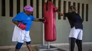 Dua nenek berlatih memukul samsak saat latihan tinju "Boxing Grannies" di Cosmo City di Johannesburg (19/9). Nenek-nenek ini berlatih dengan pelatih Claude Maphosa dan mengklaim bahwa mereka sudah lebih kuat dari sebelumnya. (AFP Photo/Gulshan Khan)