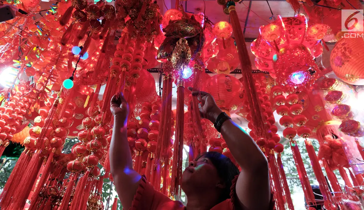 Pengunjung melihat pernak-pernik Imlek yang dijual di sebuah kios di kawasan Glodok, Jakarta, Kamis (25/1). Mereka menjual aneka barang seperti lampion, angpao, gantungan pintu, kucing rejeki, kaos, Pohon Meihua dan tulisan Fu. (Liputan6.com/JohanTallo)