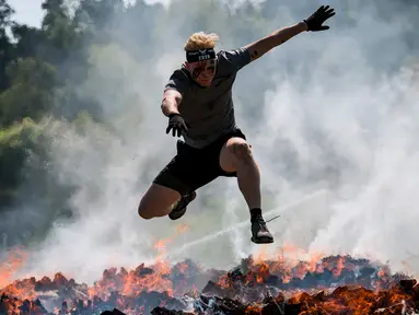 Dua pria menyeberangi rintangan api saat mereka mengikuti kompetisi Tough Viking di Stockholm, Swedia (12/5). Dalam lomba ini peserta harus menempuh jarak 8 km dengan 26 rintangan berat. (AFP/Jonathan Nackstrand)