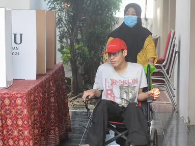 Penyandang disabilitas bersama pendamping menggunakan hak pilihnya pada Pemilihan Kepala Daerah (Pilkada) Serentak 2004 di Tempat Pemungutan Suara (TPS) 31 kawasan Lebak Bulus, Jakarta Selatan, Rabu (27/11/2024). (merdeka.com/Arie Basuki)