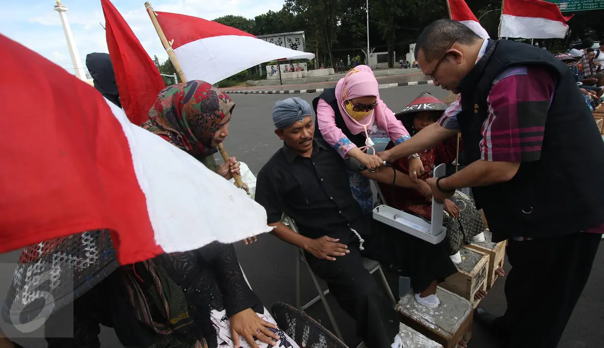 Petugas kesehatan memeriksa kondisi pengunjuk rasa yang melakukan aksi menyemen kaki di depan Istana Negara, Jakarta, Rabu (15/3). Aksi tersebut sebagai bentuk penolakan berdirinya pabrik semen di Pati. (Liputan6.com/Immanuel Antonius)
