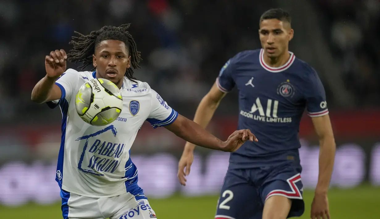 <p>Bek Troyes, Yasser Larouci berebut bola dengan bek Paris Saint Germain (PSG) Achraf Hakimi pada matchday ke-36 Ligue 1 musim 2021-22 di Parc de Princes pada laga lanjuta Ligue 1, Senin (9/5/2022) dini hari WIB. PSG harus puas meraih hasil imbang 2-2 saat menjamu klub papan bawah, Troyes. (AP Photo/Christophe Ena)</p>