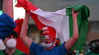 Suporter Timnas Italia mengibarkan bendera saat pertandingan melawan Turki di stadion Olimpico, Roma (Andreas Solaro/AFP)