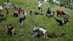 Sejumlah peserta saling berjatuhan saat mengejar gulungan keju yang diturunkan dari atas bukit Cooper Hill dalam kompetisi tahunan, Cheese Rolling di Brockworth, Gloucestershire, Inggris, 30 Mei 2016. (Adrian DENNIS/AFP)