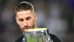 Bek Real Madrid, Sergio Ramos, berpose dengan trofi Piala Super Eropa usai timnya menumbangkan Manchester United (MU) 2-1 di Skopje, Macedonia, Selasa (8/8). Ini merupakan gelar Piala Super Eropa keempat bagi Real Madrid. (Dimitar DILKOFF / AFP)