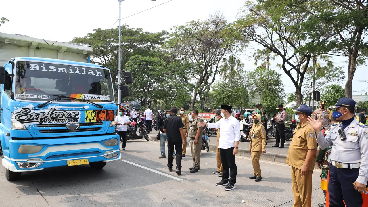 Petugas memberikan stiker khusus untuk kendaraan yang lolos penyekatan. (Dian Kurniawan/Liputan6.com)