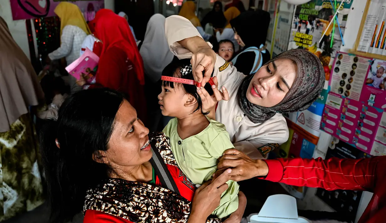 Seorang petugas kesehatan mengukur lingkar kepala bayi dalam program pemeriksaan kesehatan bulanan untuk anak-anak di sebuah pusat layanan terpadu di Banda Aceh, Senin,  10 Agustus 2026. (AFP/ Chaideer Mahyuddin)