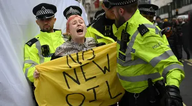 Petugas polisi memindahkan seorang aktivis iklim yang memprotes proyek ladang minyak Rosebank di Laut Utara lepas pantai Skotlandia, di luar InterContinental London Park Lane, London, 18 Oktober 2023. 18 Oktober 2023. (Daniel LEAL/AFP)