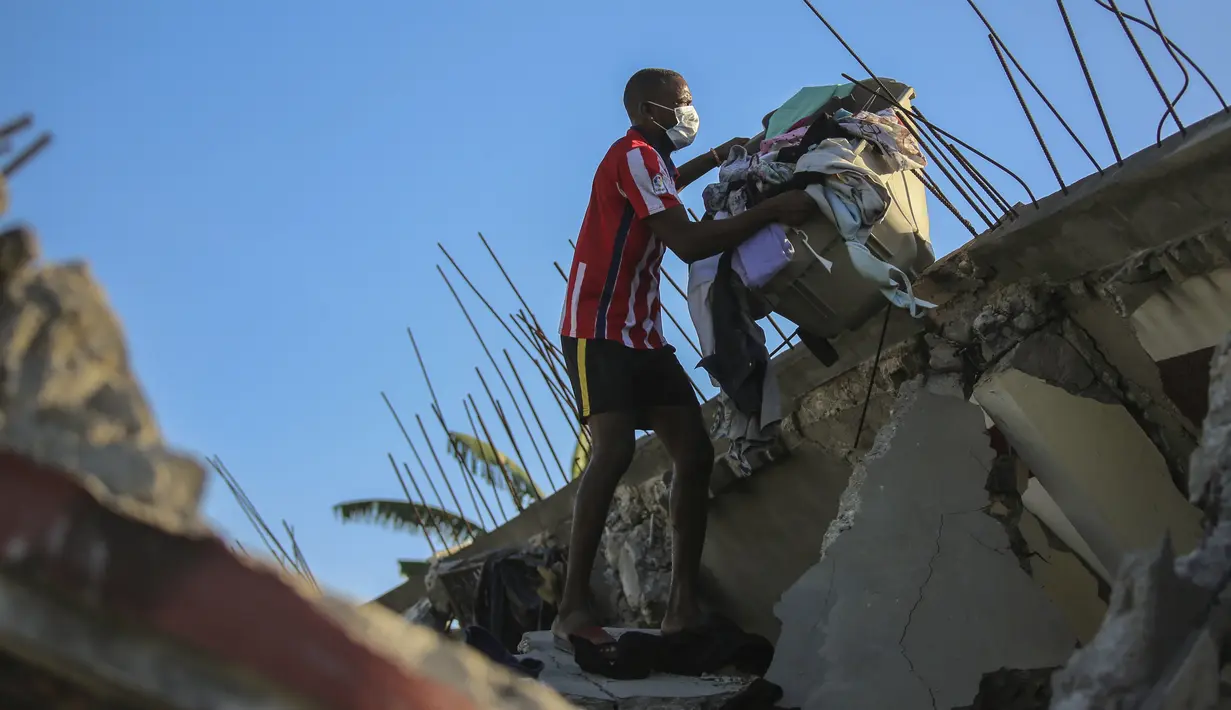 Seorang pria mengambil barang-barang dari rumahnya yang hancur akibat gempa di Les Cayes, Haiti, Sabtu (14/8/2021). Wilayah Negara Haiti diguncang gempa berkekuatan magnitudo 7,1 pada Sabtu, 14 Agustus 2021 pukul 08.29.10 waktu setempat yang menewaskan lebih dari 300 jiwa. (AP Photo/Joseph Odelyn)