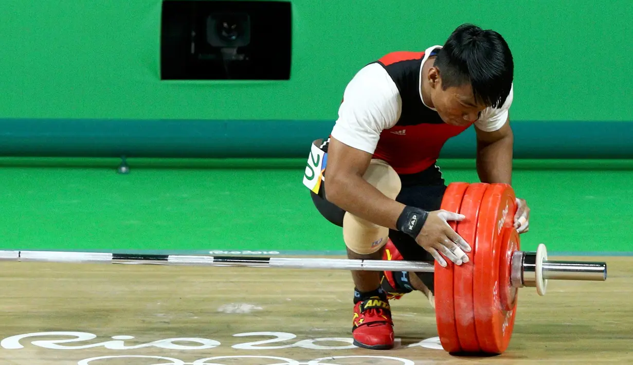 Deni melihat barbel yang gagal diangkatnya saat berlaga di Olimpiade 2016, Brasil, Rabu (10/8). Deni yang memiliki berat tubuh 69.38kg, tidak bermain di kelasnya, dan lawan-lawannya memiliki tubuh jauh lebih berat. (REUTERS/Athit Perawongmetha)