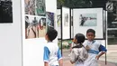 Siswa SD Negeri Menteng 01 mengamati karya foto yang dipamerkan dalam pameran fotografi Rekam Jakarta di Taman Menteng, Kamis (29/8/2019). Kegiatan tersebut dalam rangka edukasi bagi siswa mengenal profesi foto jurnalistik. (Liputan6.com/Marsha Aulia)