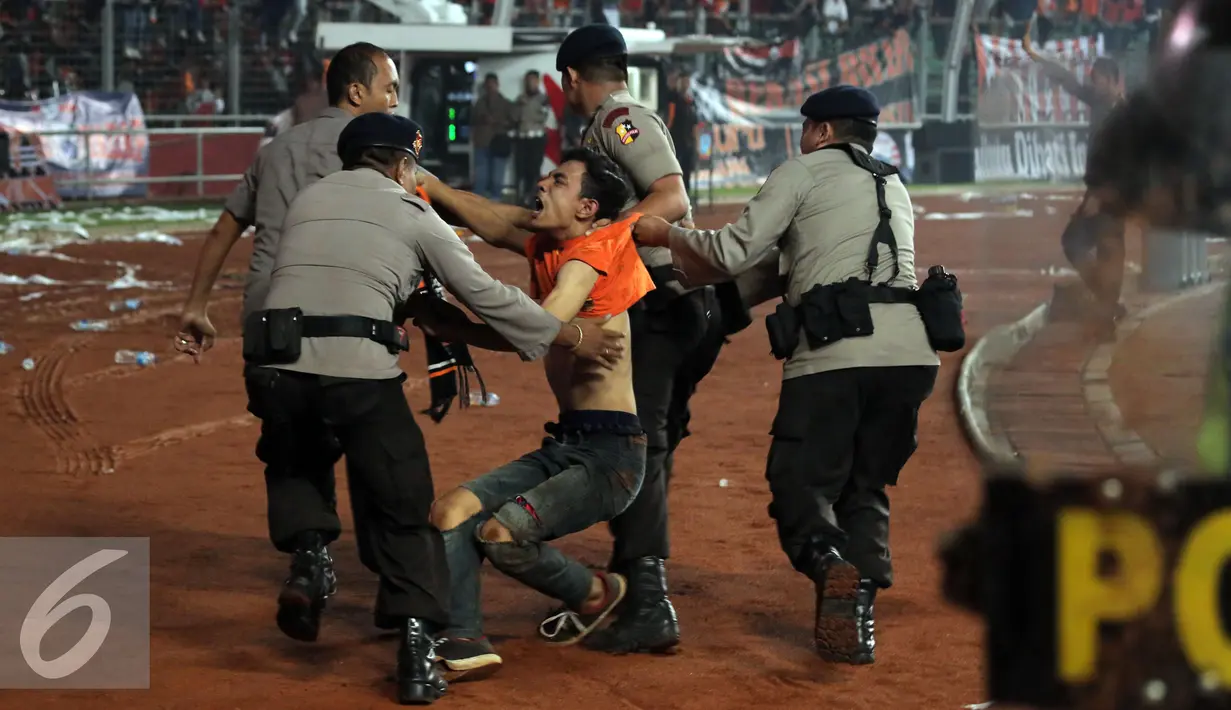 Petugas kepolisian mengamankan seorang suporter usai terlibat bentrok saat laga Persija melawan Sriwijaya FC pada lanjutan Torabika Soccer Championship presented by IM3 Ooredoo diStadion GBK Jakarta, Jumat (24/6). (Liputan6.com/Helmi Fithriansyah)