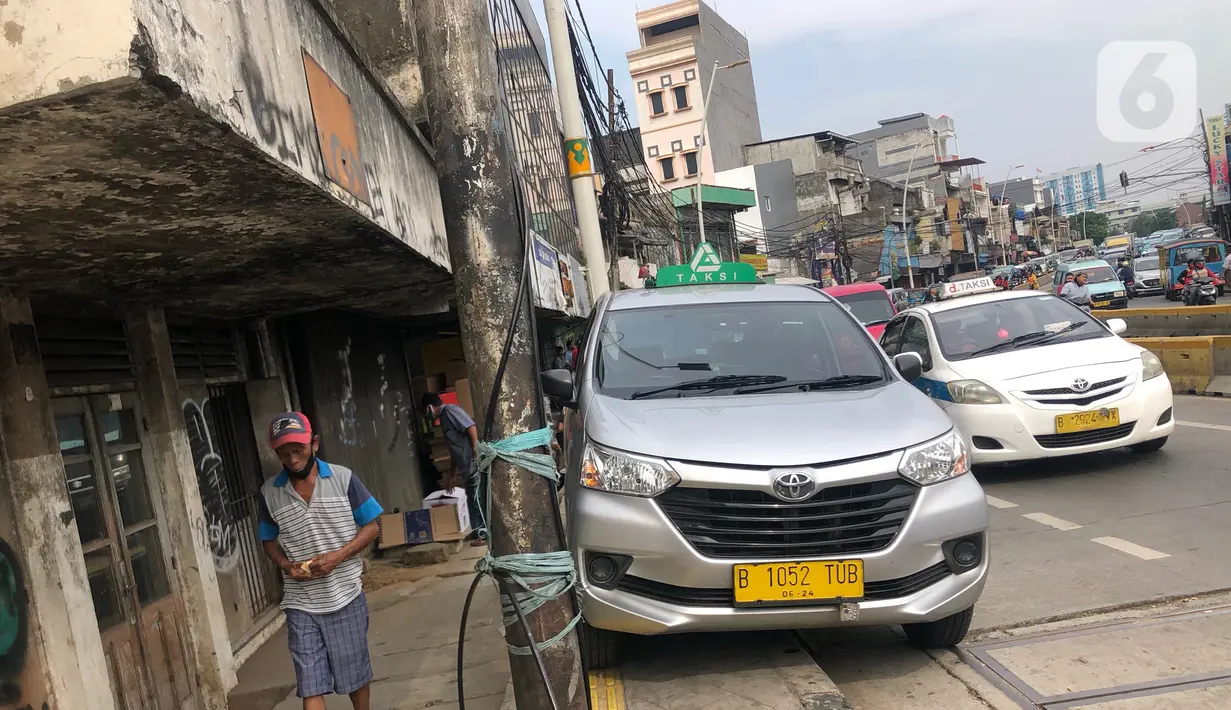 Sebuah taksi terparkir di sekitar trotoar kawasan Jatinegara, Jakarta, Selasa (14/7/2020). Tidak adanya sanksi tegas membuat trotoar yang telah diperlebar tersebut justru dimanfaatkan sebagai lahan parkir liar yang mengganggu ketertiban umum. (Liputan6.com/Immanuel Antonius)