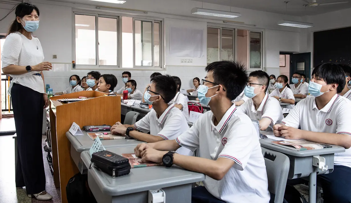 Para siswa mendengarkan guru pada hari pertama semester baru di Wuhan, Provinsi Hubei, China, 1 September 2021. Pemerintah China memutuskan pemberlakuan belajar tatap muka setelah percaya diri menangani pandemi COVID-19. (STR/AFP)