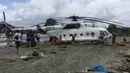 Warga berusaha menggali lumpur yang menimbun helikopter Mi-17 milik BNPB pasca banjir bandang di Kabupaten Sentani, Jayapura, (17/3). Banjir bandang Sentani menewaskan 70 orang dan puluhan luka-luka. (AFP/Netty Dharma Somba)