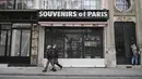 Orang-orang berjalan di depan toko suvenir yang tutup di Paris (22/3/2021).  Penduduk Paris dan beberapa wilayah Prancis lainnya menghabiskan akhir pekan pertama mereka di bawah penguncian terbatas selama sebulan.  (AP Photo/Lewis Joly)