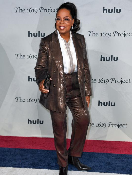 <p>Oprah Winfrey menghadiri pemutaran perdana The 1619 Project di Academy Museum of Motion Pictures, Los Angeles, California, Amerika Serikat, 26 Januari 2023. Wanita berusia 68 tahun tersebut mengenakan atasan berkancing putih di dalam mantel cokelatnya. (VALERIE MACON/AFP)</p>
