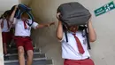 Sejumlah siswa SD menggunakan tas sekolah mereka untuk melindungi diri selama latihan tsunami di Tanjung Benoa dekat Denpasar di pulau resor Bali (15/8). (AFP Photo/ Sonny Tumbelaka)