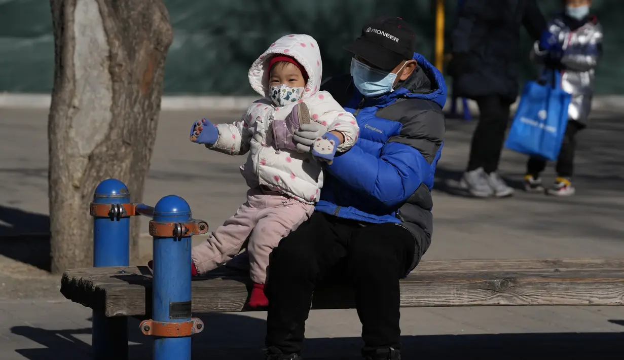 Seorang pria mengangkat seorang anak di sebuah taman di Beijing, China (13/1/2022). Jumlah bayi yang lahir di China terus menyusut tahun lalu, seiring menyusutnya jumlah tenaga kerja. (AP Photo/Andy Wong)