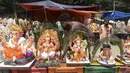 Seorang perajin memajang patung Dewa Ganesha untuk dijual di kios pinggir jalan di Hyderabad, India, Kamis (9/9/2021). Patung dewa Hindu berkepala gajah tersebut banyak dijual jelang Festival Ganesh Chaturthi. (NOAH SEELAM/AFP)