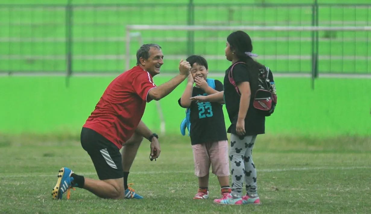 Pelatih Arema Cronus, Milomir Seslija, tampak asyik mengajak buah hati Hamka Hamzah yang bernama Gava dan Gwen bermain saat sela-sela latihan di Stadion Gajayana, Malang, Sabtu (4/6/2016). (Bola.com/Iwan Setiawan)