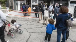 Orang tua mengantre di pusat vaksinasi bersama anak-anak mereka yang akan menerima vaksin covid-19 di ibu kota Siprus, Nicosia, Minggu (2/1/2022). Siprus memulai vaksinasi untuk anak-anak berusia antara 5 hingga 11 tahun, di tengah lonjakan tajam kasus virus corona. (Iakovos Hatzistavrou / AFP)