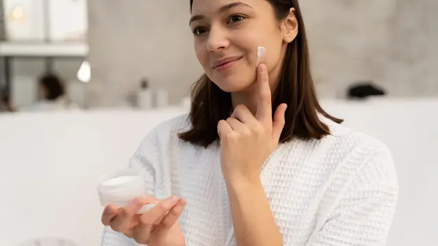 Seorang perempuan sedang mengaplikasikan skincare di wajahnya (Foto Dok: Freepik/freepik)