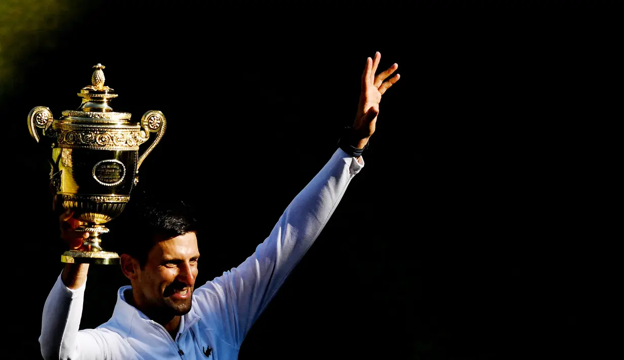 Novak Djokovic berhasil merengkuh gelar juara Wimbledon 2022 usai menundukkan seterunya asal Australia, Nick Kyrgios lewat skor 4-6 6-3 6-4 7-6(3). Berkat keberhasilan tersebut Djokovic membawa pulang gelar ketujuh tunggal putra Wimbledon sepanjang kariernya. (AFP/Daniel Leal)