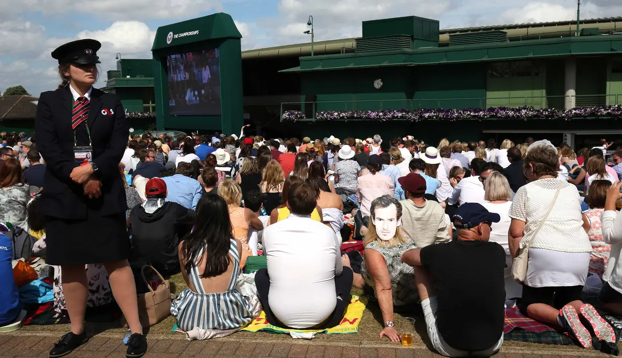 Petugas berjaga dekat ribuan penonton yang menyaksikan laga Andy Murray melawan Milos Raonic pada final tunggal putra  Wimbledon Championships 2016 di The All England Lawn Tennis Club,  Wimbledon, London, (10/7/2016).  (AFP/Justin Tallis)