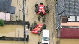 Pasukan Bela Diri Jepang menyusuri banjir saat operasi penyelamatan di Takeo, Prefektur Saga, Jepang, Rabu (28/8/2019). Perintah evakuasi 240 ribu warga di Kyushu dan sekitarnya dikeluarkan usai seorang warga dilaporkan tewas akibat terkena imbas hujan deras di Kota Saga. (Kyodo News via AP)