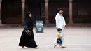 Seorang pria bersama istri dan anaknya berjalan di masjid Jama  di kawasan lama New Delhi, India (30/7/2019). Masjid Jama sendiri terletak di sisi jalan raya yang sangat ramai di Delhi Tua, yaitu Jalan Chadni Chowk. (AFP Photo/Money Sharma)