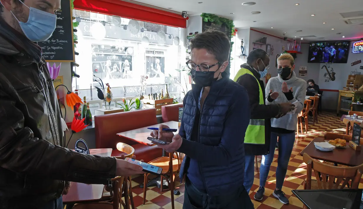 Seorang pria menjalani pemeriksaan kartu vaksin covid-19, di sebuah restoran di Lille, Prancis utara, Senin (24/1/2022). Aturan yang mulai berlaku pada hari Senin mewajibkan “vaksin pass” bagi warga yang ingin mengakses tempat publik. (AP Photo/Michel Spingler)