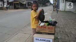 Seorang anak mengambil mi instan dan telur gratis di Jalan Raya Cibubur-Bojong Kulur, Bogor, Kamis (9/4/2020). Di beberapa pinggir jalan Kawasan Jabotabek saat ini banyak aksi solidaritas oleh warga dengan menyediakan bahan makanan gratis di tengah pandemi virus corona. (merdeka.com/Arie Basuki)