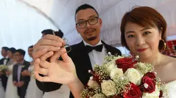Pasangan pengantin asal Tiongkok menunjukkan cincin kawin saat mengikuti pernikahan massal di Kolombo, Sri Lanka (17/12). Acara nikah massal ini bertujuan untuk meningkatkan pariwisata di Sri Lanka (AFP Photo/Ishara S. Kodikara)
