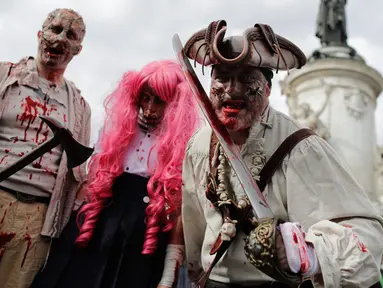 Tiga orang peserta mengenakan kostum zombie berpose saat mengikuti "Zombie Walk" di Paris, Prancis (7/10). Acara ini diadakan setiap tahun dan manjadi daya tarik untuk wisatawan. (AFP Photo/Thomas Samson)