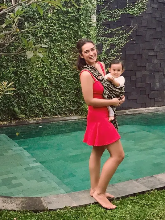 Kalau yang satu ini, Alexandra berada di tepi kolam renang sambil menggendong anaknya. Ia juga tetap seksi dengan mini dress merah dan sangat memerlihatkan lekuk tubuhnya yang seksi. (Instagram/got_alex)
