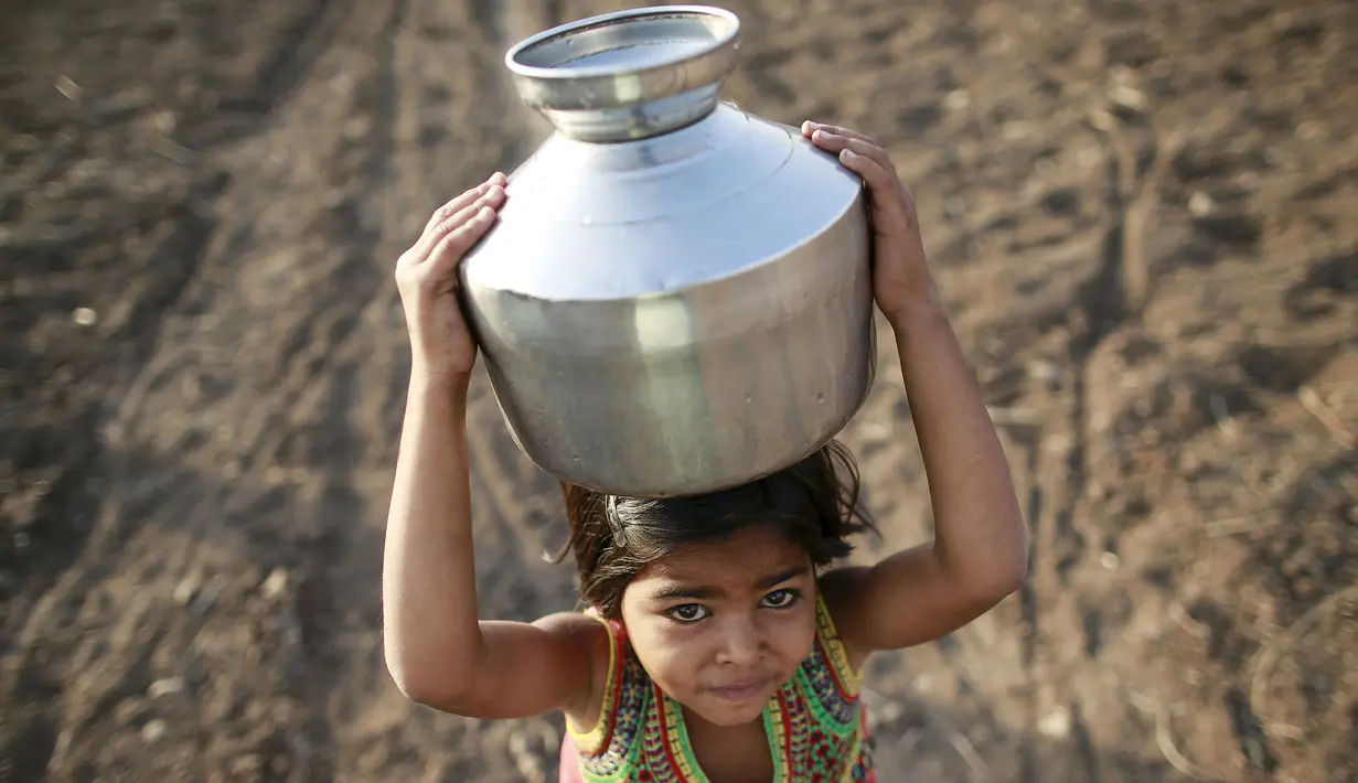 Seorang anak membawa kendi berisi air di Latur, India, (17/4). Akibat bencana kekeringan warga mengalami krisis air bersih yang melanda India. (REUTERS/Danish Siddiqui)
