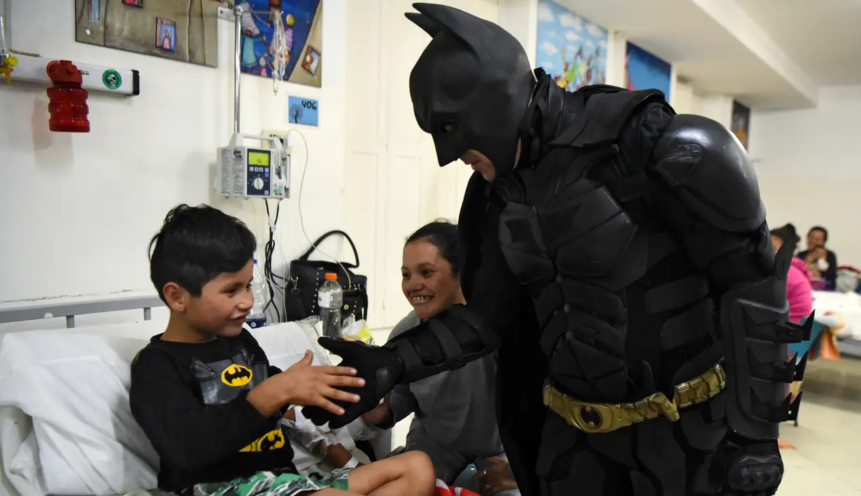 Seorang pria berkostum Batman menyalami seorang pasien anak di RS Anak 'Sor Maria Ludovica' di La Plata, Buenos Aires, Argentina, Jumat (2/6). Kehadiran Batman ini menjadi hiburan bagi anak-anak di rumah sakit tersebut. (AFP FOTO / Eitan ABRAMOVICH)