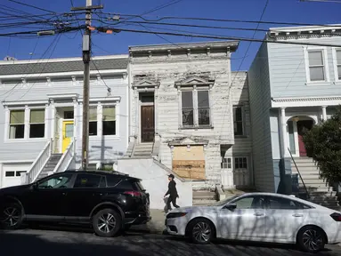 Pejalan kaki melewati rumah bergaya Victoria yang baru saja dijual di San Francisco, pada 14 Januari 2022. Rumah berusia 122 tahun yang sudah lapuk ini dipasarkan sebagai "rumah terburuk di blok terbaik" San Francisco terjual hampir 2 juta dollar AS atau sekitar Rp 28,6 miliar. (AP Photo/Jeff Chiu)