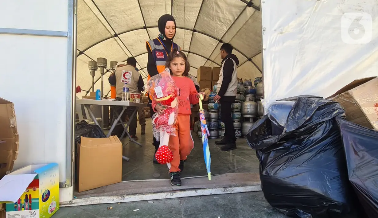Seorang anak membawa bantuan mainan yang disalurkan organisasi kemanusiaan Bulan Sabit Merah Indonesia (BSMI) di pengungsian Taman Ataturk, Kahramansan, Turki, Selasa (21/2/2023). Bantuan terdiri dari mainan anak, popok bayi, dan makanan khusus bayi juga perlengkapan selama musim dingin untuk anak-anak. (Liputan6.com/Andry Haryanto)