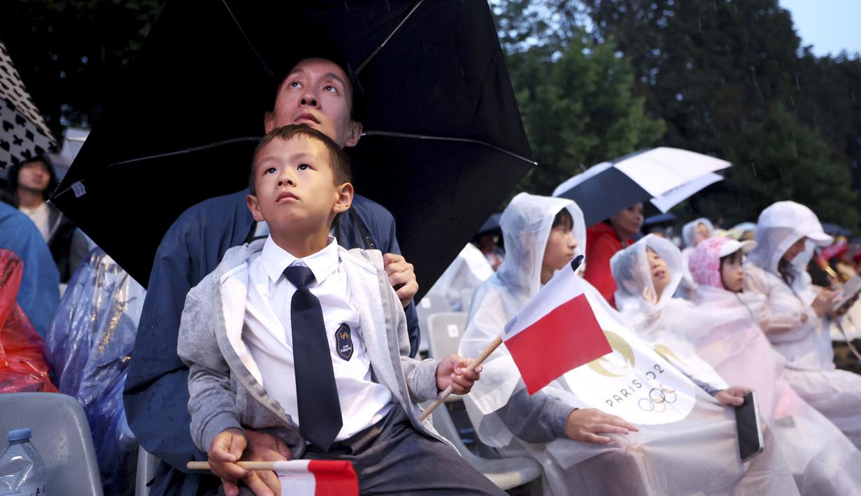 Warga tampak antusias menyaksikan acara pembukaan Olimpiade 2024 di Paris, Sabtu (27/7/2024). (Steph Chambers/Pool Photo via AP)