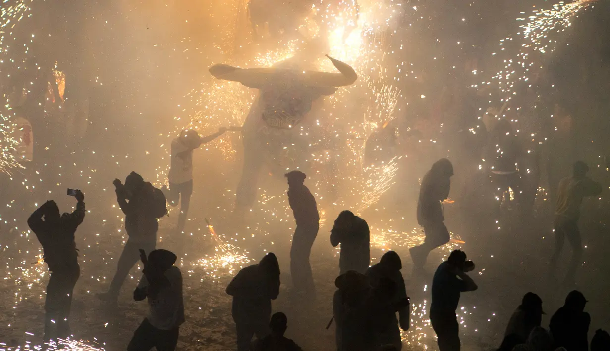 Sejumlah pengunjung berlari di dekat kembang api yang meledak dari banteng "Torito" dalam perayaan tradisional tahunan San Juan de Dios di Tultepec, Meksiko (8/3). (AP Photo/Rebecca Blackwell)