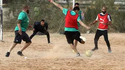 Seorang pemain menembak bola saat bermain di lapangan tanah sebelum buka puasa selama bulan Ramadhan, di ibu kota Libya, Tripoli (24/4/2021). (AFP/Mahmud Turkia)