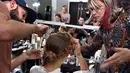 Seorang model saat ditata rambutnya sebelum tampil di atas panggung French Lingerie Show di Paris, Prancis, Minggu (22/1). (AFP Photo/Alain Jocard)