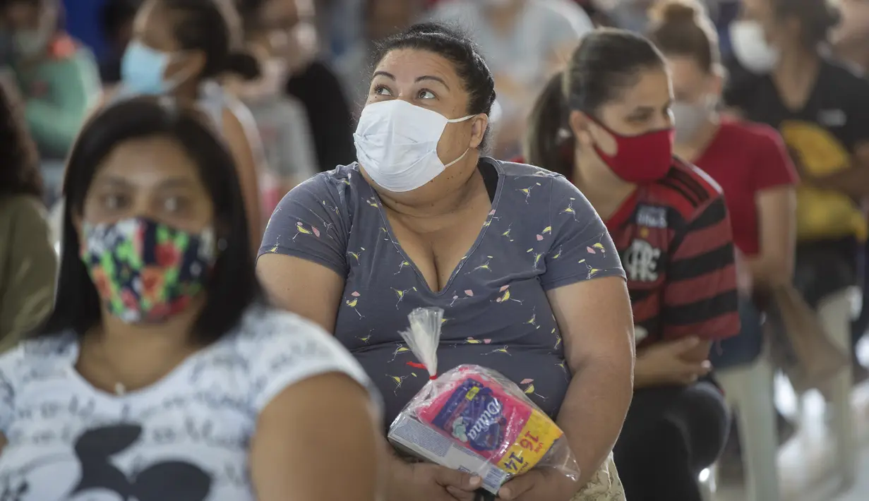 Sejumlah wanita duduk setelah menerima sumbangan pembalut dan perlengkapan kebersihan perempuan lainnya di tengah pandemi COVID-19 di favela Paraisopolis, di Sao Paulo, Brasil (24/5/2021). Sumbangan ini disediakan oleh LSM lokal "G10 Favelas". (AP Photo/Andre Penner)