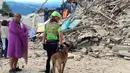 Seorang pria dan petugas penyelamat serta anjing pelacak berdiri di depan puing bangunan rumah yang rusak akibat gempa  6,2 SR di Amatrice, Italia tengah, Kamis (24/8). Sedikitnya enam orang tewas dalam bencana ini. (REUTERS/Emiliano Grillotti)
