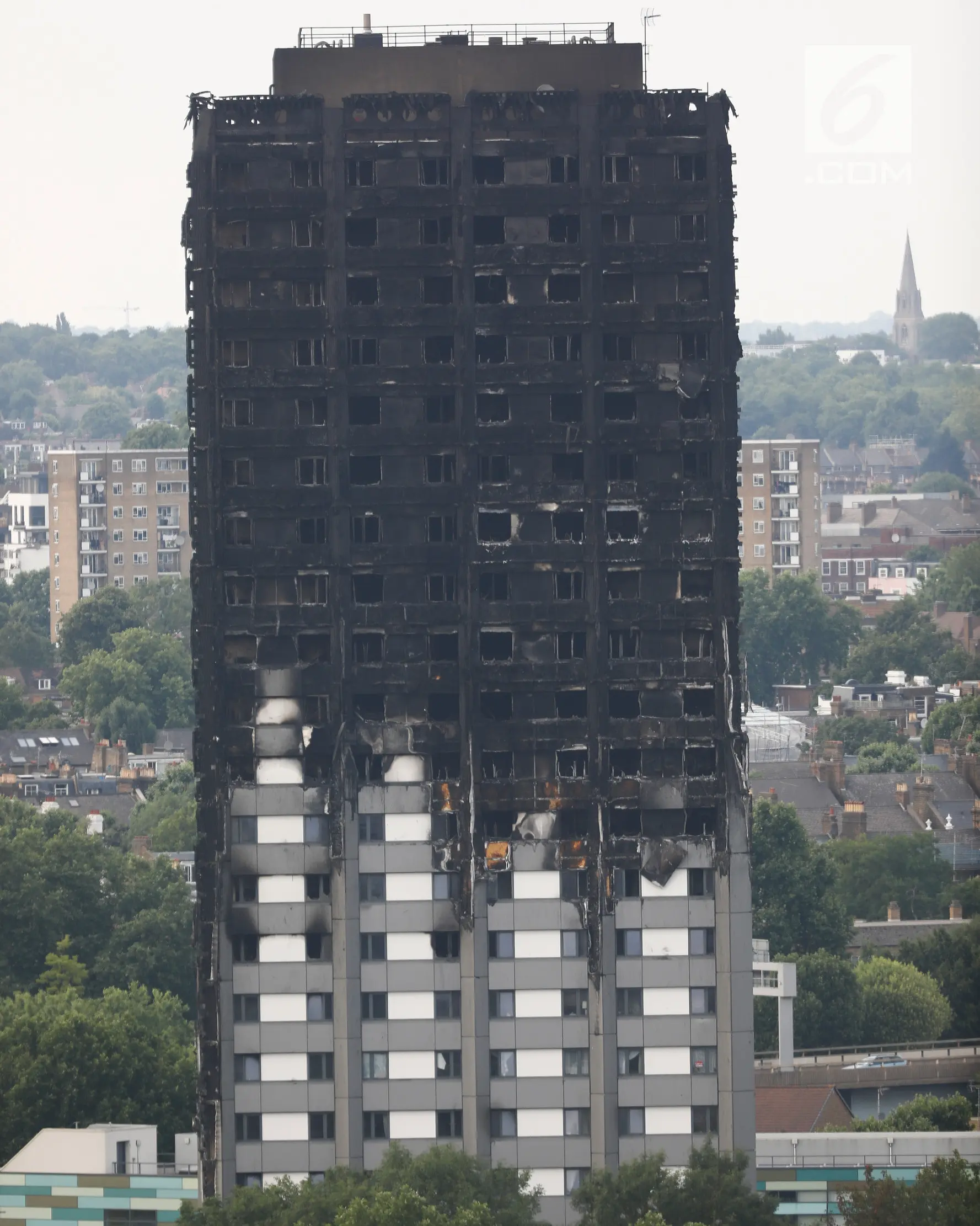 Kerusakan bangunan apartemen Grenfell Tower di London terlihat dari utara Kensington, Minggu (18/6). Gedung apartemen Grenfell Tower yang terbakar pada lepas tengah malam Rabu 14 Juni 2017 lalu dikhawatirkan roboh usai habis dilahap api. (TOLGA AKMEN/AFP)