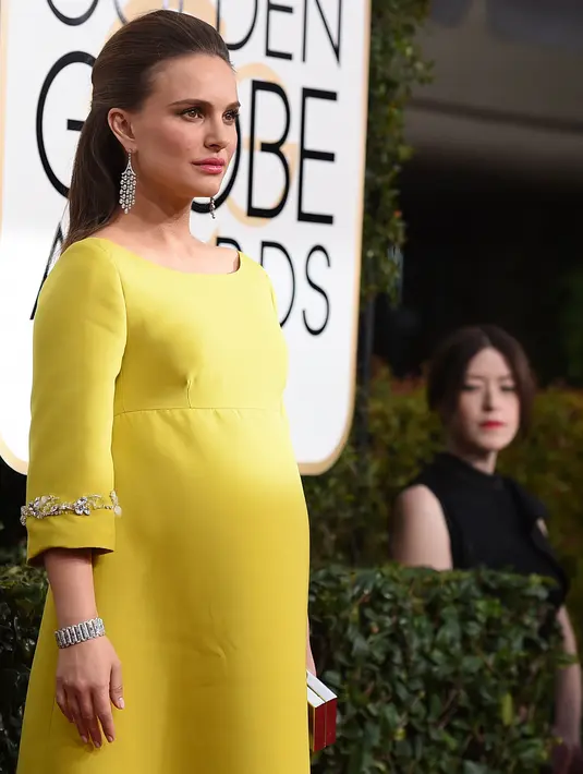 Aktris Natalie Portman berpose untuk fotografer di karpet merah ajang Golden Globe Awards 2017 di California, AS, Minggu (8/1). Natalie menampilkan perutnya yang sedang hamil dengan mengenakan pakaian gaun kuning. (Jordan Strauss/Invision/AP)
