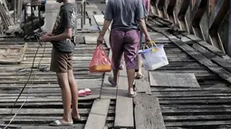 Warga melintasi jembatan dari kayu yang menjadi penghubung antara Jalan Karet Pasar Baru VII, Karet Tengsin dan Jalan Pam Baru, Bendungan Hilir, Tanah Abang, Rabu (30/1). (Liputan6.com/Faizal Fanani)